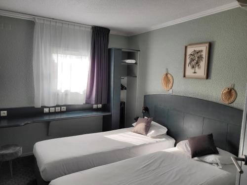 Cette chambre comprend 2 lits et une fenêtre. dans l'établissement Kyriad Direct Arles, à Arles