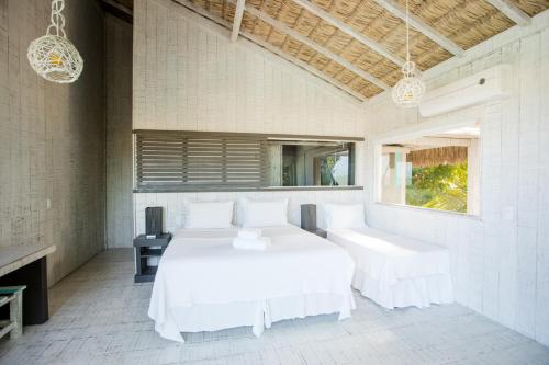 a white bedroom with a large bed and a window at Beach Houses Moitas in Amontada