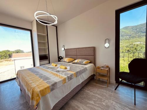 a bedroom with a bed and a chair and large windows at Adriatic Dream in Tivat