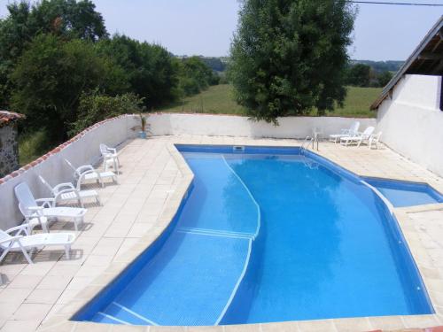 a swimming pool with white chairs and a swimming pool at GersGites in Justian