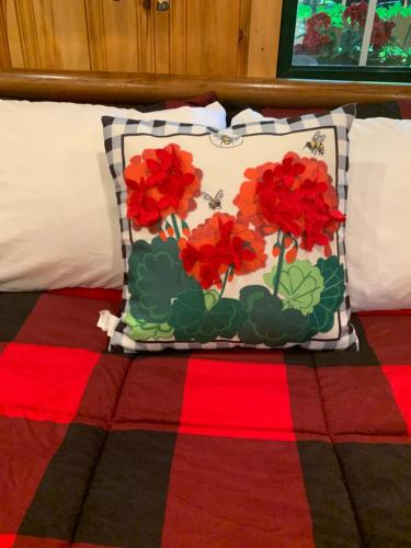 a pillow with red flowers on it sitting on a bed at The croquet cabin your year round romantic escape in Boulder Junction