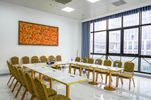 a meeting room with tables and chairs and a painting at Magnificent International Hotel in Shanghai