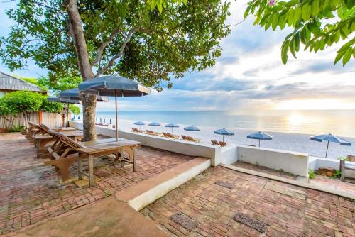 a picnic table with umbrellas on the beach at Veranda Lodge in Hua Hin