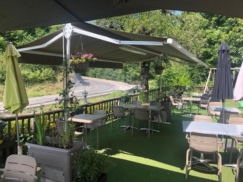 patio ze stołami, krzesłami i parasolami w obiekcie Bar Hotel Restaurant le Margeriaz w mieście Les Déserts