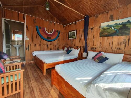 two beds in a room with wooden walls at Tavan View Homestay in Sapa