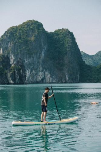 a man standing on a paddle board in the water at Lan Ha Floating Homestay in Cat Ba