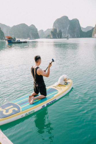 a man taking a picture of a dog on a paddle board in the water at Lan Ha Floating Homestay in Cat Ba