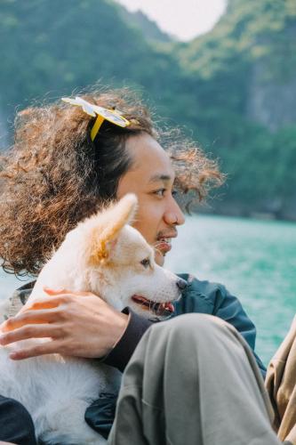 a man sitting on a boat holding a dog at Lan Ha Floating Homestay in Cat Ba