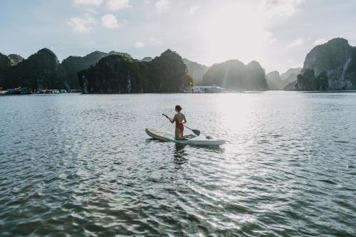 a man on a paddle board in the water at Lan Ha Floating Homestay in Cat Ba