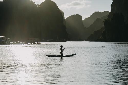 a person standing on a canoe in the water at Lan Ha Floating Homestay in Cat Ba