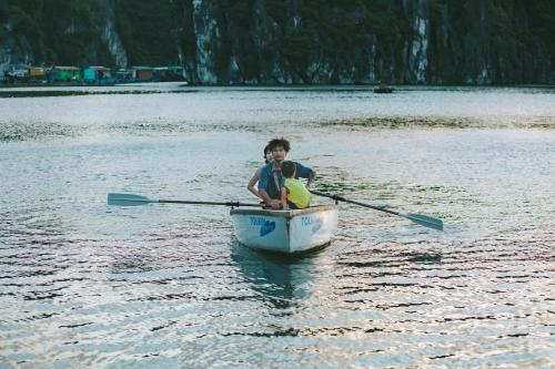 a boy is rowing a boat in the water at Lan Ha Floating Homestay in Cat Ba