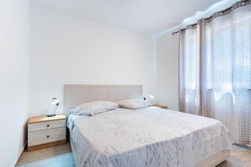 a white bedroom with a bed and a window at New 4 star apartment M&A in town Cres in Cres