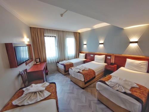 イスタンブールにあるオリエント ミントゥール ホテルのベッド3台とデスクが備わるホテルルームです。