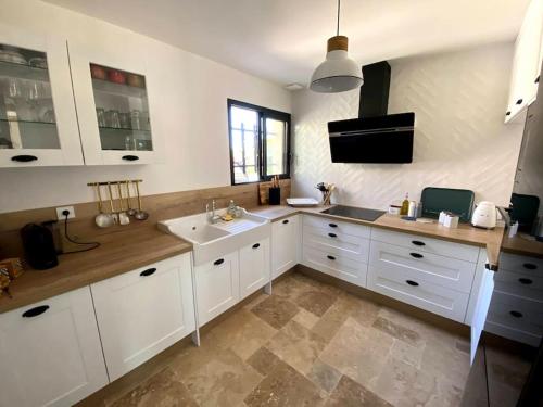 une cuisine avec des armoires blanches et un évier dans l'établissement Mas de charme avec piscine au coeur des Alpilles, à Eygalières