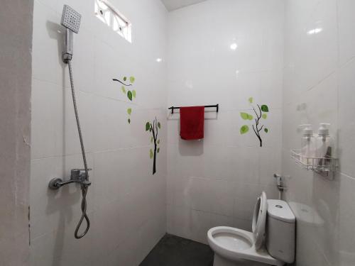 a white bathroom with a toilet and a red towel at Ambarukmo Green Hill / MA 8 in Yogyakarta