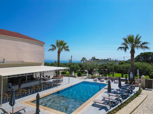 una piscina in un resort con sedie e palme di Remezzo Studios & Apartments ad Amoudi