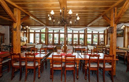 a dining room with wooden tables and chairs and a chandelier at Hotel Jelinek in Špindlerův Mlýn