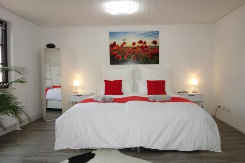 una camera da letto con un grande letto bianco con cuscini rossi di HAPPY-HOMES - Up to 5 - Küche - W-LAN - Netflix - Honig - Terrasse ad Altenstadt