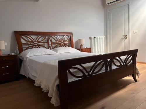 Un dormitorio con una gran cama de madera con sábanas blancas. en Casa Cavour, en Montecatini Terme