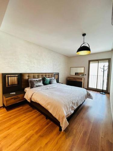 1 dormitorio con 1 cama grande y suelo de madera en Vue sur le Parc Prestigia Fès, en Fez