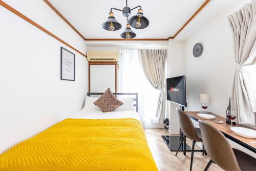 1 dormitorio con cama amarilla, mesa y sillas en エステラス大阪ウエスト101 en Osaka