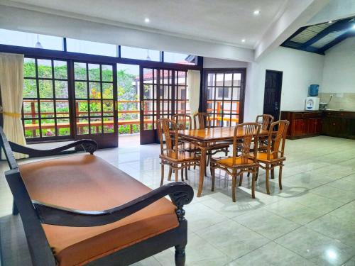 een eetkamer met een tafel, stoelen en ramen bij In Villa Garden Resort in Batu