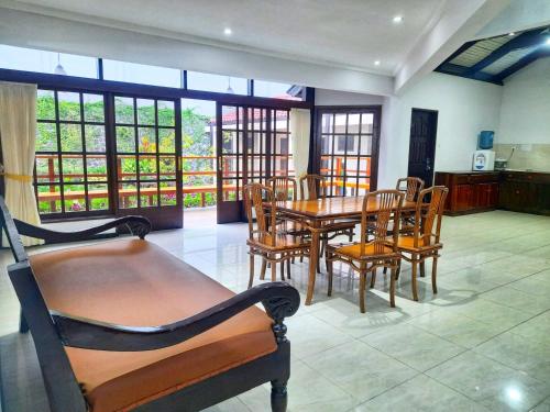 a dining room with a table and chairs and windows at In Villa Garden Resort in Batu