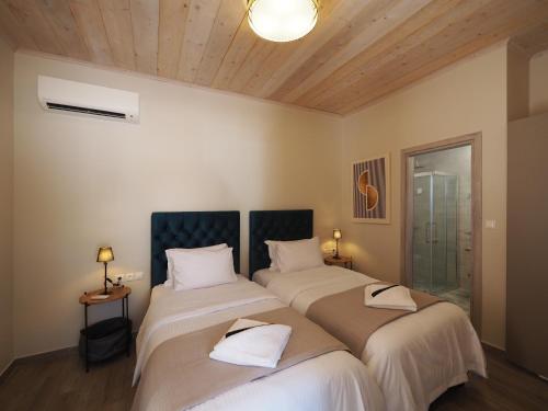 two beds in a room with wooden ceilings at Terra Di Pietra Exclusive Suites & Apartments in Areopolis