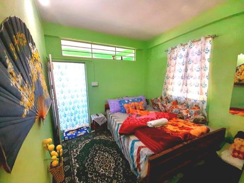 een groene kamer met een bed en een raam bij International Youth Hostel and Homestay Kurseong Bazar in Kurseong