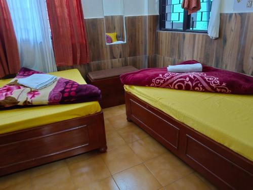 two beds in a room with yellow and purple sheets at International Youth Hostel and Homestay Kurseong Bazar in Kurseong