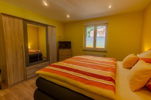 Dormitorio amarillo con cama y TV en Ferienwohnung Philipp, en Traben-Trarbach