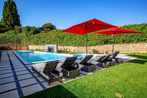 a group of chairs and umbrellas next to a pool at LOTUS VILLA 2, ALBUFEIRA in Albufeira