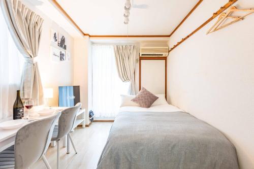 a bedroom with a bed and a table and a window at エステラス大阪ウエスト102 in Osaka