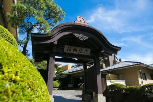 a gate in front of a building with writing on it at Furuya Ryokan in Atami