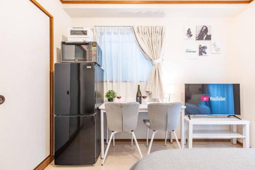 a kitchen with a refrigerator and a table with chairs at エステラス大阪ウエスト102 in Osaka