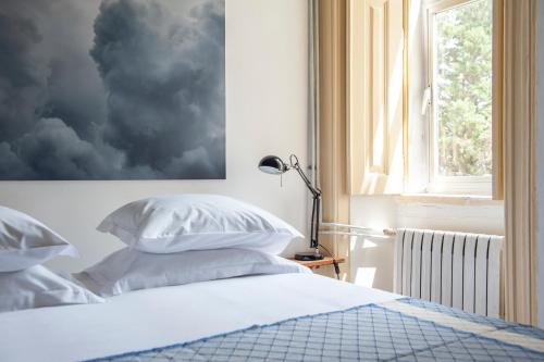 a bedroom with a bed with white pillows and a window at Cheese & Wine Lapa in Lisbon