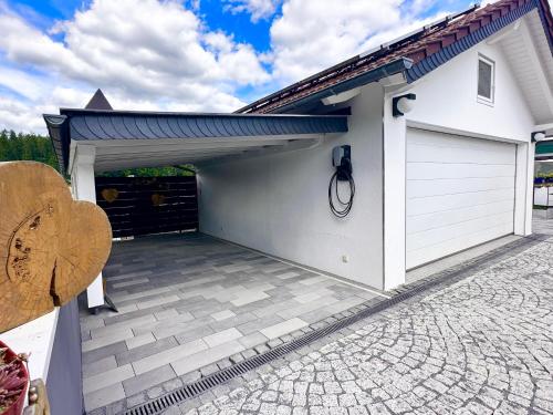 a garage with awning and a driveway at Ferienhaus zur Waldauer Höhe mit 3 SZ, 120qm & 40qm Balkon in Schleusingen