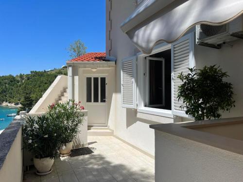 a white building with two potted plants on a balcony at Apartments Domani in Omiš