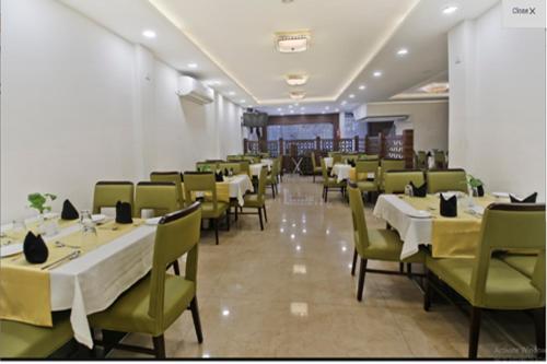 a dining room with white tables and green chairs at Hotel King's way in Amritsar