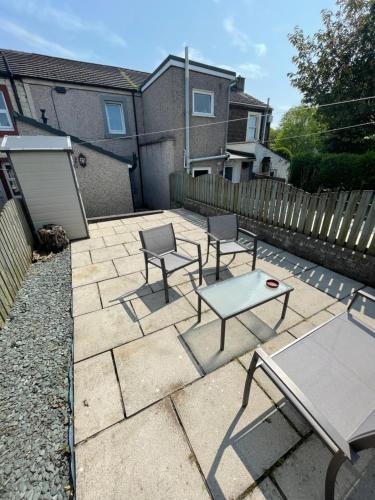 a patio with two chairs and a table and a bench at Flosh Cottage Lake District in Cleator