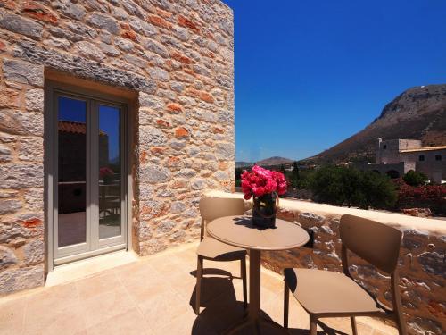 a table and chairs on a patio with a stone wall at Terra Di Pietra Exclusive Suites & Apartments in Areopolis