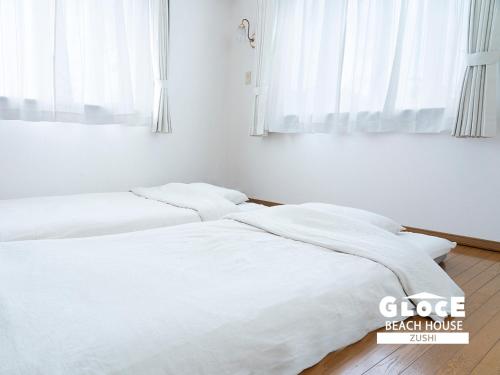 逗子市にあるGLOCE 逗子ビーチハウス l ZUSHI BEACH HOUSEの白い壁と窓が備わる客室で、ベッド2台が備わります。