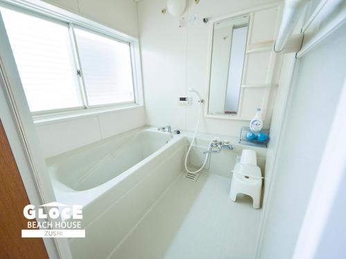 uma casa de banho branca com uma banheira e uma janela em GLOCE 逗子ビーチハウス l ZUSHI BEACH HOUSE em Zushi