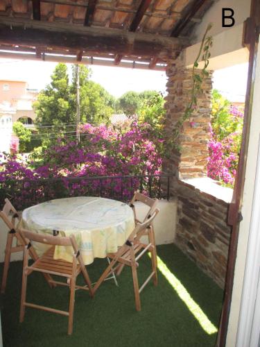 une table et des chaises sur une terrasse avec des fleurs violettes dans l'établissement B Appartement proche plage, centre, commerces, à Cavalaire-sur-Mer