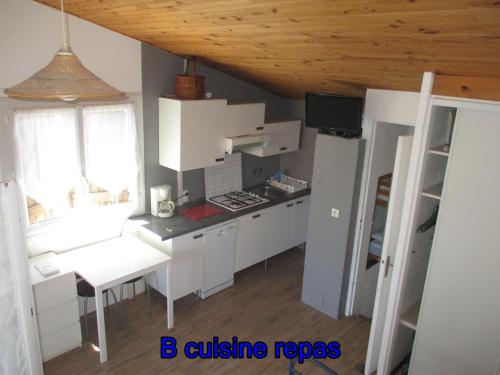 une cuisine avec des placards blancs, une table et une fenêtre dans l'établissement B Appartement proche plage, centre, commerces, à Cavalaire-sur-Mer