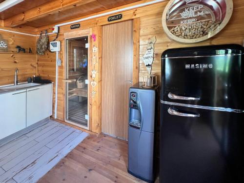 een keuken met een zwarte koelkast in een huisje bij Jordan River Village in Menaẖemya