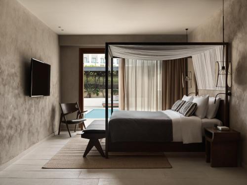 a bedroom with a bed and a tv and a pool at Lindian Village All Inclusive Resort Rhodes,Curio Collection in Kiotari
