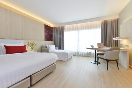 a hotel room with two beds and a desk at Centre Point Plus Hotel Pratunam in Bangkok