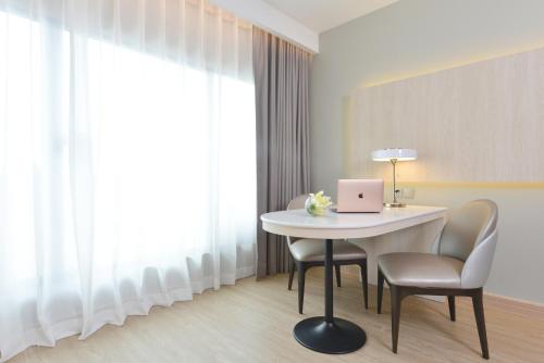 a room with a table and chairs with a laptop on it at Centre Point Plus Hotel Pratunam in Bangkok