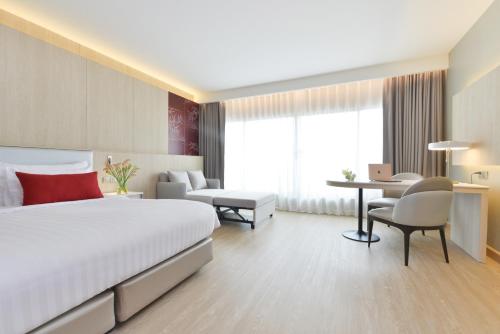 a hotel room with a large bed and a desk at Centre Point Plus Hotel Pratunam in Bangkok